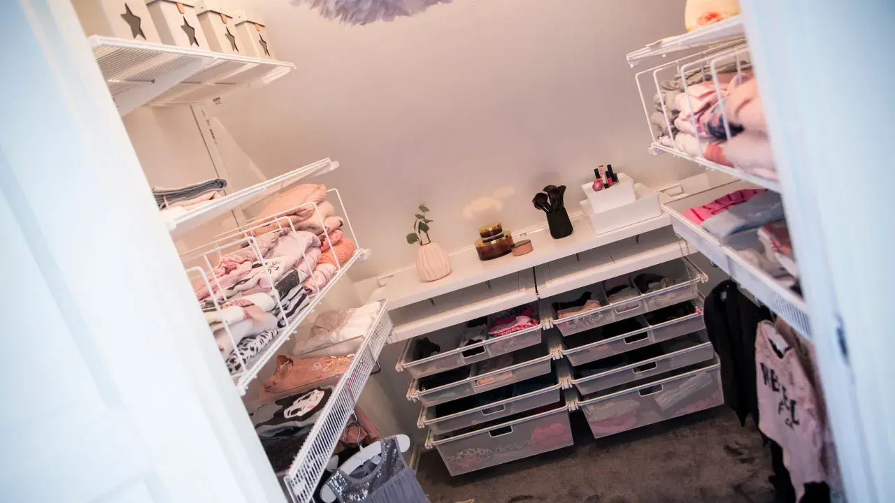 Organiserad walk in closet med snedtak. Hyllor och lådor fyllda med kläder och accessoarer.