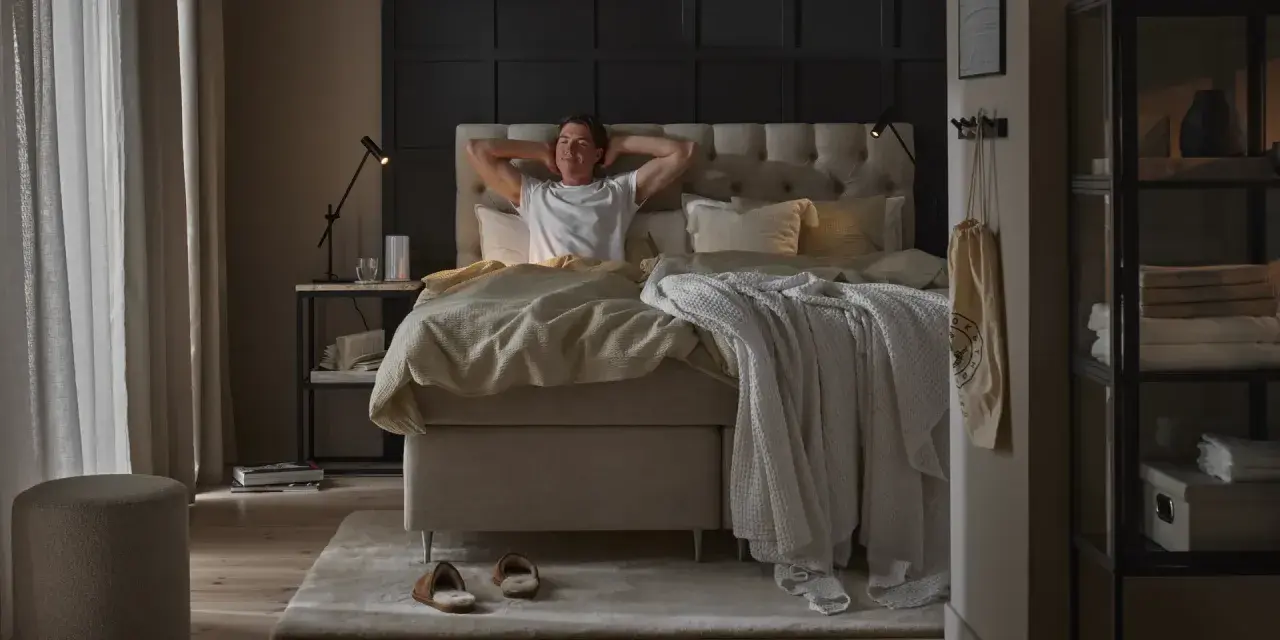 Man sträcker sig i en stor, inbjudande säng. En perfekt start på dagen för att sleepwell.