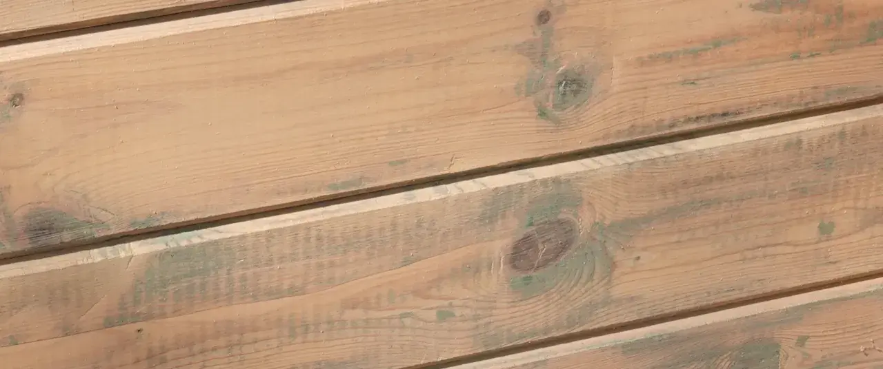 Träpanel med en varm, brun lasyr och inslag av grönaktiga fläckar, som ger en rustik känsla.