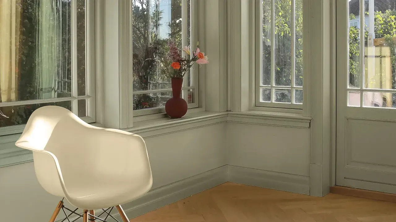 En ljus hall med en vit stol och en vas med blommor på fönsterbrädan. Väggarna är nymålade i en lugn grön nyans.
