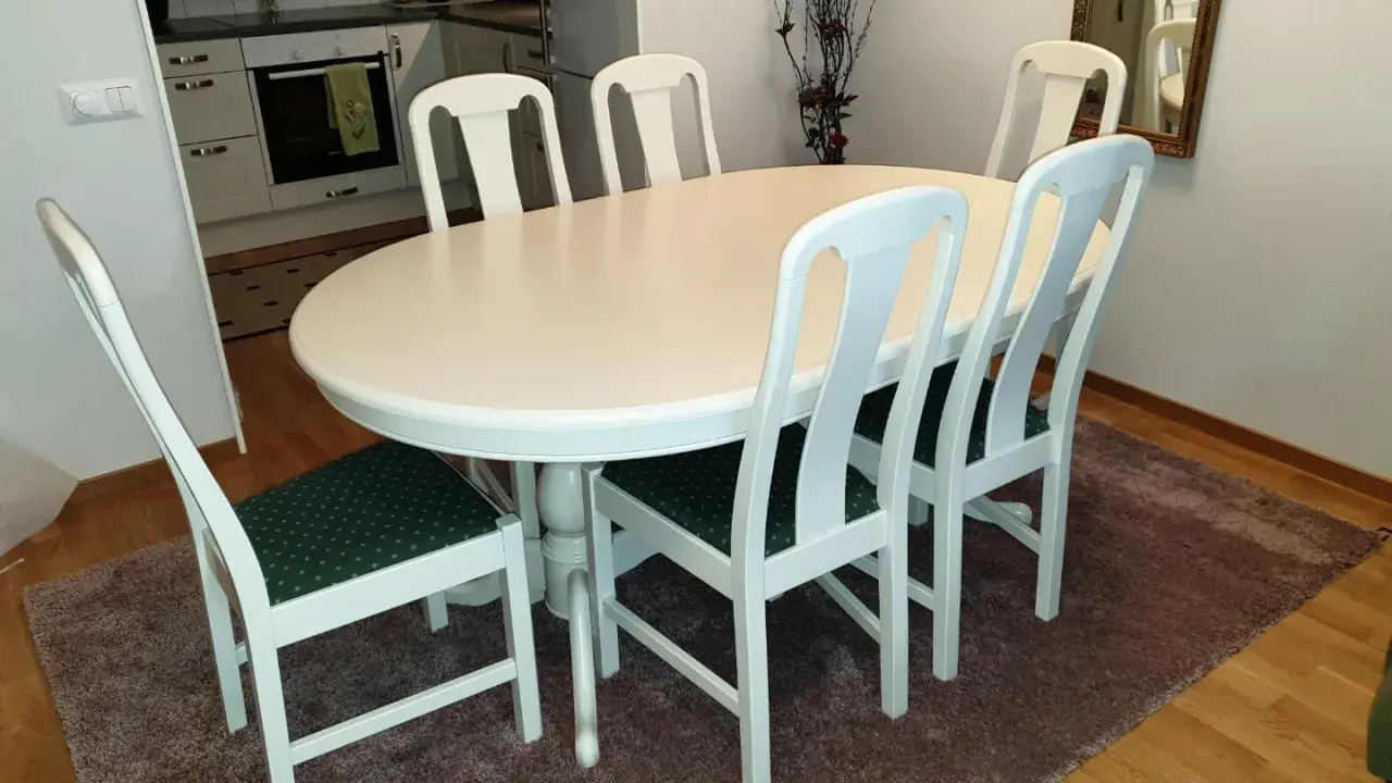 Vitt runt matbord med sex stolar med gröna dynor. Perfekt för att lacka om stolar och ge dem nytt liv.