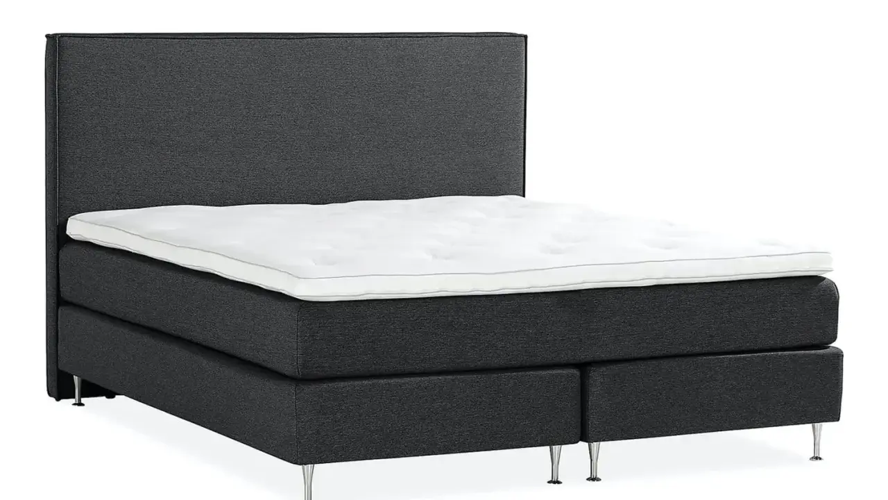 En mörkgrå, modern kontinentalsäng med en vit bäddmadrass och eleganta metallben. Denna elite säng är en dröm för alla som söker komfort.