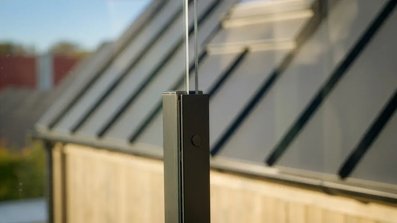 Detaljbild av en stolpe för att montera vindskydd. Glaspanelen syns i bakgrunden.