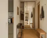 En ljus och inbjudande vit hall med en spegelgarderob, en smal konsol och en bänk. En matta i jute ger värme.