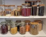 Välordnat skafferi med glasburkar fyllda med nötter, torkad frukt, frön och baljväxter. Perfekt för att organisera skafferi.