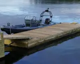 En nybyggd brygga med en mörkgrå RIB-båt förtöjd. Perfekt för att njuta av sommaren vid vattnet.