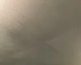 Grått, flammigt tak efter målning. Ytan är ojämn med synliga penseldrag.