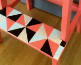 En pall med geometriskt mönster i orange, svart, vitt och ljusblått. Ett kreativt sätt att måla pall!