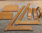 Delar av en Stokke stol ligger utspridda på en matta, redo att måla om.