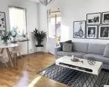 Mysig etta med grå soffa, vitt soffbord och en rund matplats. Konst på väggarna ger personlighet.