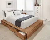 Säng med smart förvaring vid sängen i form av utdragbara lådor i trä. Enkel och stilren design.