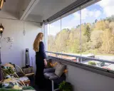 En kvinna njuter av utsikten från en mysig balkong med fin balkong inredning. Våren är här med grönska och sol.