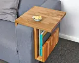 Ett smart diy soffbord i trä som hängs över armstödet på en grå soffa. Perfekt för att förvara böcker och ha en skål med kex nära till hands.