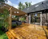 Träaltan med pergola och loungegrupp ger härlig altan inspiration. Solrosor och grönska ramar in.
