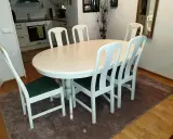 Vitt runt matbord med sex stolar med gröna dynor. Perfekt för att lacka om stolar och ge dem nytt liv.