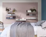 Ett mysigt sovrum med en säng med grå filt, en bänk med en trähund och hyllor med växter och lådor. Perfekt inspiration för att måla sovrum i milda färger.