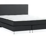 En mörkgrå, modern kontinentalsäng med en vit bäddmadrass och eleganta metallben. Denna elite säng är en dröm för alla som söker komfort.