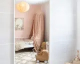 A child's closet with clothes and baskets, a pink bedroom with a bed and canopy, and a white wall with a window.