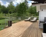Nyligen oljad altan med solstolar och grill. Vacker utsikt över grönskande skog.