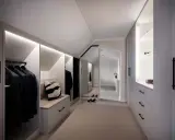 En stilren walk-in-closet med inbyggd sittbänk och garderobslösningar som utnyttjar kattvindens vinklar.