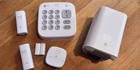 Ett eufy larm test med en kontrollpanel, sensorer och en basstation på ett trägolv.
