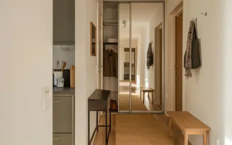 En ljus och inbjudande vit hall med en spegelgarderob, en smal konsol och en bänk. En matta i jute ger värme.