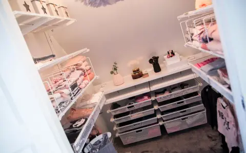 Organiserad walk in closet med snedtak. Hyllor och lådor fyllda med kläder och accessoarer.