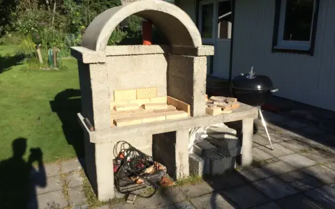 Bygga grill av tegelstenar. En nybyggd betonggrill med tegelstenar i eldstaden, redo för sommarens grillfester.
