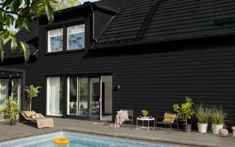Ett modernt svart hus med pool och uteplats. Perfekt för att måla i solsken och njuta av sommaren.
