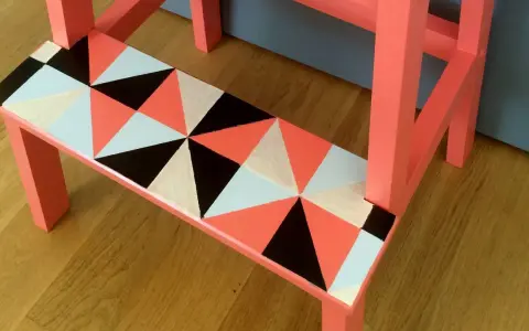 En pall med geometriskt mönster i orange, svart, vitt och ljusblått. Ett kreativt sätt att måla pall!