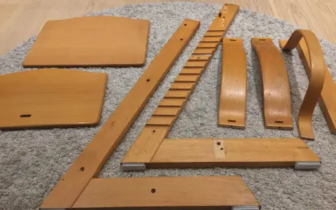 Delar av en Stokke stol ligger utspridda på en matta, redo att måla om.