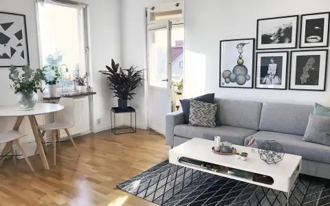 Mysig etta med grå soffa, vitt soffbord och en rund matplats. Konst på väggarna ger personlighet.