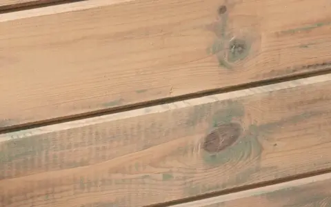 Träpanel med en varm, brun lasyr och inslag av grönaktiga fläckar, som ger en rustik känsla.