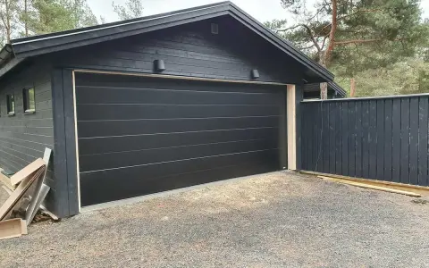 Nyinstallerad svart garageport montering på ett mörkt garage.