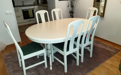 Vitt runt matbord med sex stolar med gröna dynor. Perfekt för att lacka om stolar och ge dem nytt liv.