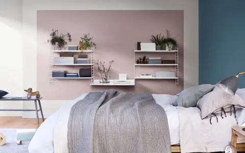 Ett mysigt sovrum med en säng med grå filt, en bänk med en trähund och hyllor med växter och lådor. Perfekt inspiration för att måla sovrum i milda färger.