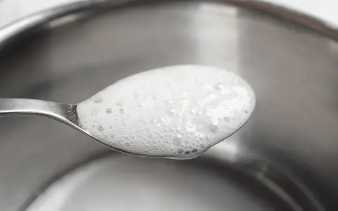 En sked med skummande bikarbonat utan aluminium, redo att användas för rengöring eller bakning.