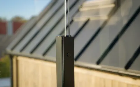 Detaljbild av en stolpe för att montera vindskydd. Glaspanelen syns i bakgrunden.
