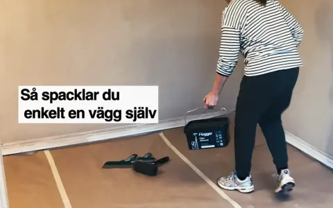 Person med hink med spackel och verktyg för att slipa och jämna ut en vägg.