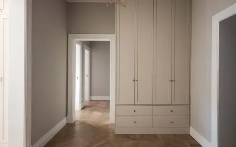 En hall med en stor garderob i ljusgrått och fiskbensparkett. Perfekt grå hall inspiration för ett modernt hem.