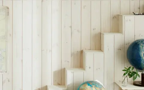 En vägg med ljus träpanel ger en mysig känsla. En gammal sjökarta hänger på ena sidan, medan en trappliknande hylla på andra sidan visar upp jordglober och böcker. Perfekt panel inomhus inspiration för äventyrliga själar.