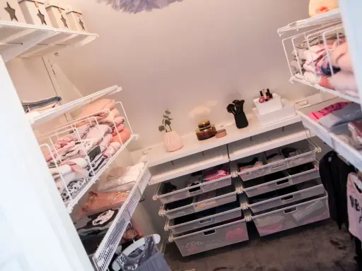 Organiserad walk in closet med snedtak. Hyllor och lådor fyllda med kläder och accessoarer.