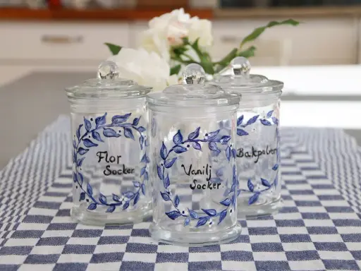 Tre vackra glasburkar med blå blommotiv, perfekta för att måla på glasburkar och förvara socker eller bakpulver.