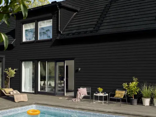 Ett modernt svart hus med pool och uteplats. Perfekt för att måla i solsken och njuta av sommaren.