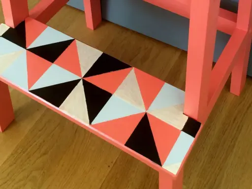 En pall med geometriskt mönster i orange, svart, vitt och ljusblått. Ett kreativt sätt att måla pall!