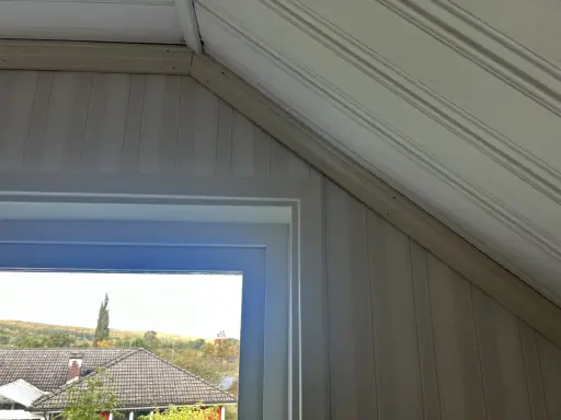 Takskena i snedtak med panelklädda väggar. Fönstret ger utsikt över hus och höstfärgad natur.
