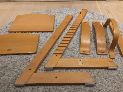 Delar av en Stokke stol ligger utspridda på en matta, redo att måla om.