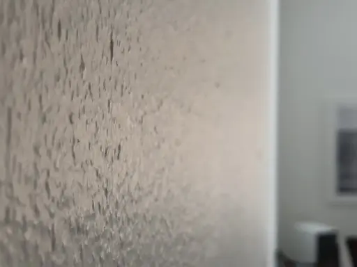 Närbild på en vägg där man har bredspacklat på tapet. Ytan är ojämn och texturerad.