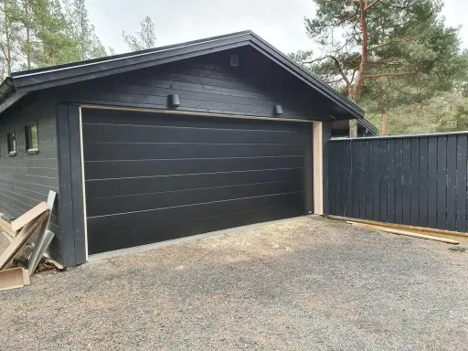 Nyinstallerad svart garageport montering på ett mörkt garage.
