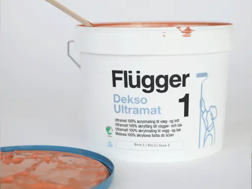 En hink Flügger Dekso Ultramat färg, med en träpinne som rör om. Jämför sidenmatt vs matt finish.